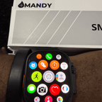 Mandy Android Smartwatch M12 with colorful app icons on a wrist, with 'MANDY' branding in the background.